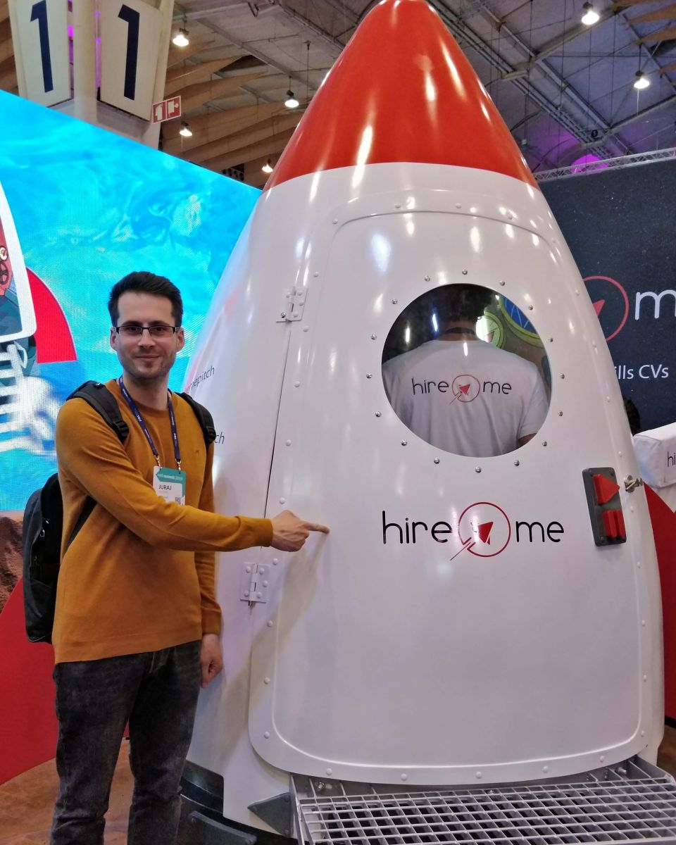 Juraj Kucera pointing at a “hire me” sign on a rocket at Web Summit